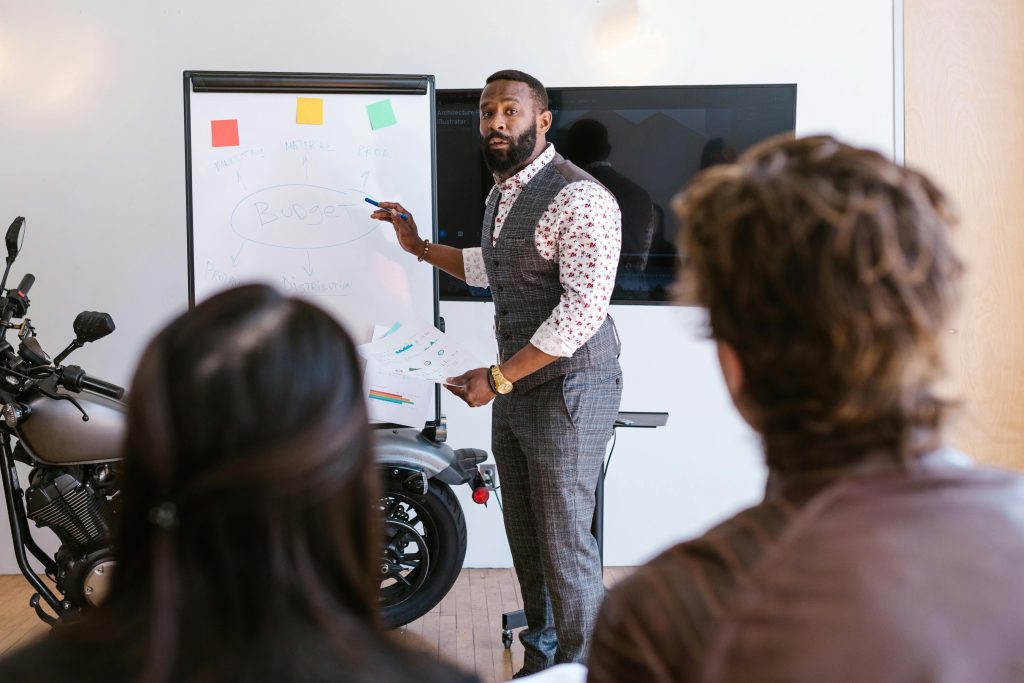 An executive discussing budget stability pointing at a whiteboard